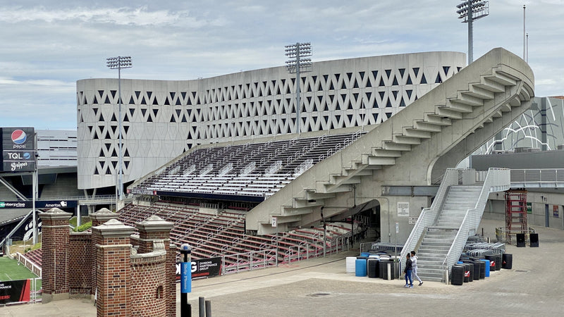 The concrete stands of Nippert Stadium and the patterned Lindner Center wall behind them, with old brick gate pillars in front