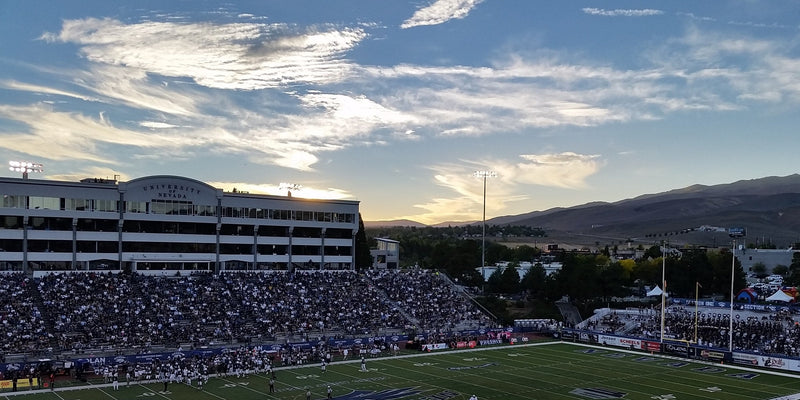Mackay Stadium in Reno at sunset during a game, with the press box on the left and the hills behind the stadium