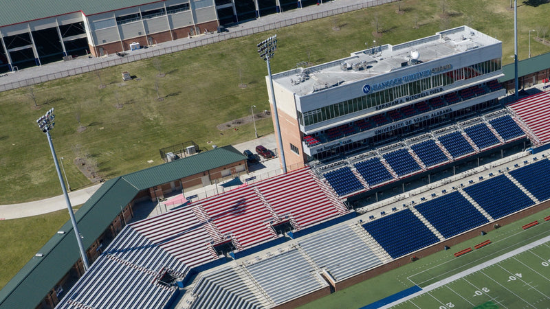 Aerial view of the west stands and press tower at Hancock Whitney Stadium in Mobile, with the stadium name on the tower