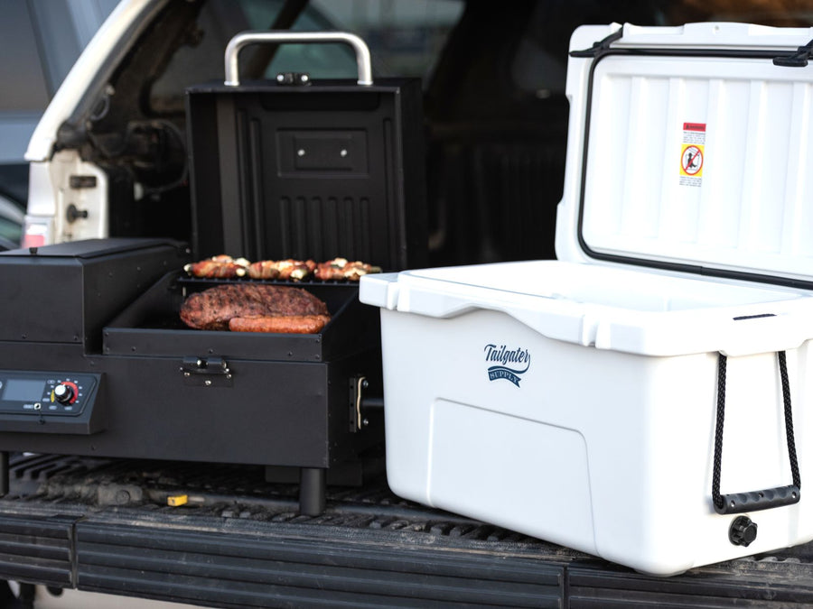 A grill and a white cooler set up in a pickup bed at the lot