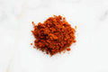 Load image into Gallery viewer, Small mound of finely ground red-orange barbecue rub on white marble
