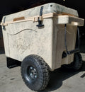 Load image into Gallery viewer, Tan cooler on the wheel kit from the other corner, a large knobby wheel on the axle and a rope handle