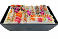 Load image into Gallery viewer, Sushi rolls, sashimi, wasabi and orchid flowers laid out on white chill boards covering a black cooler