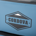 Load image into Gallery viewer, Close-up of the hexagon Cordova logo printed on the slate-blue backpack cooler's front