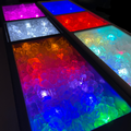 Load image into Gallery viewer, Row of cooler compartments full of ice glowing purple, white, blue, red, aqua and rainbow in the dark