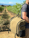 Load image into Gallery viewer, Man carrying a brown camp kitchen bag on a shoulder strap down a vineyard row