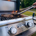 Load image into Gallery viewer, Tongs lifting steaks off the grates, seen past the two control knobs and Monument logo