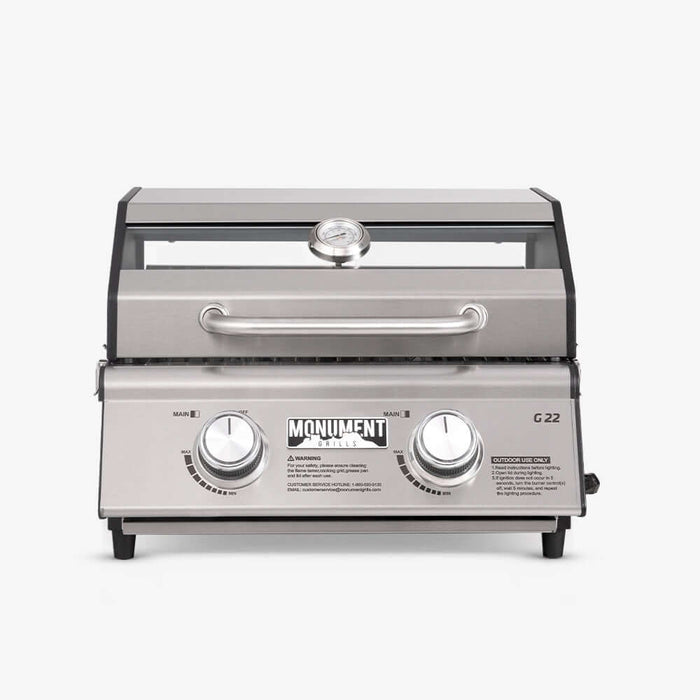 Front view of a stainless two-knob tabletop grill with a window strip in the lid and a lid thermometer