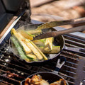 Load image into Gallery viewer, Tongs turning zucchini in a cast-iron skillet set on the grill grates