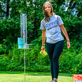 Load image into Gallery viewer, Woman in a Scorezit T-shirt holding a cornhole bag beside a staked metal scorekeeper with a tumbler in its cup holder