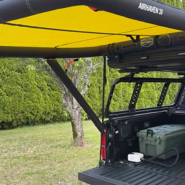 Yellow-lined AirHaven 30 awning off a pickup's bed rack, shading the tailgate and a cooler