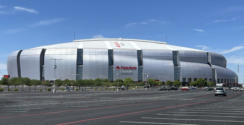 State Farm Stadium in Glendale, Arizona, behind an empty parking lot with red fire lanes