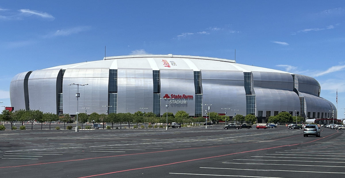 State Farm Stadium in Glendale, Arizona, behind an empty parking lot with red fire lanes