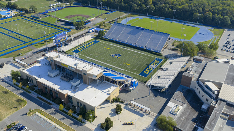 Aerial view of Delaware Stadium in Newark on a clear morning, with the Whitney Athletic Center in front and the practice fields behind