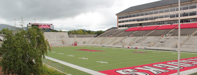 Burgess-Snow Field at AmFirst Stadium in Jacksonville, Alabama, with the press box and red seats under a cloudy sky
