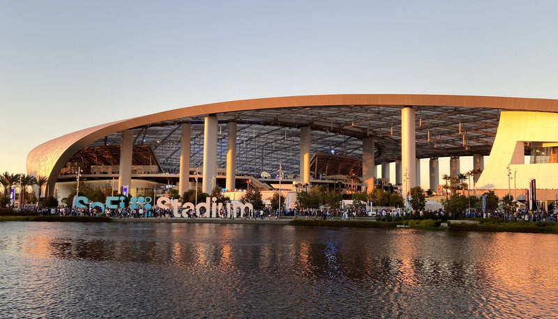 SoFi Stadium in Inglewood at sunset, seen across Lake Park