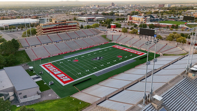 Aerial view of University Stadium in Albuquerque, with the press box, the red end zones and the city behind it