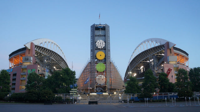 The north side of Lumen Field in Seattle at dusk, with the stadium tower between the two roof arches