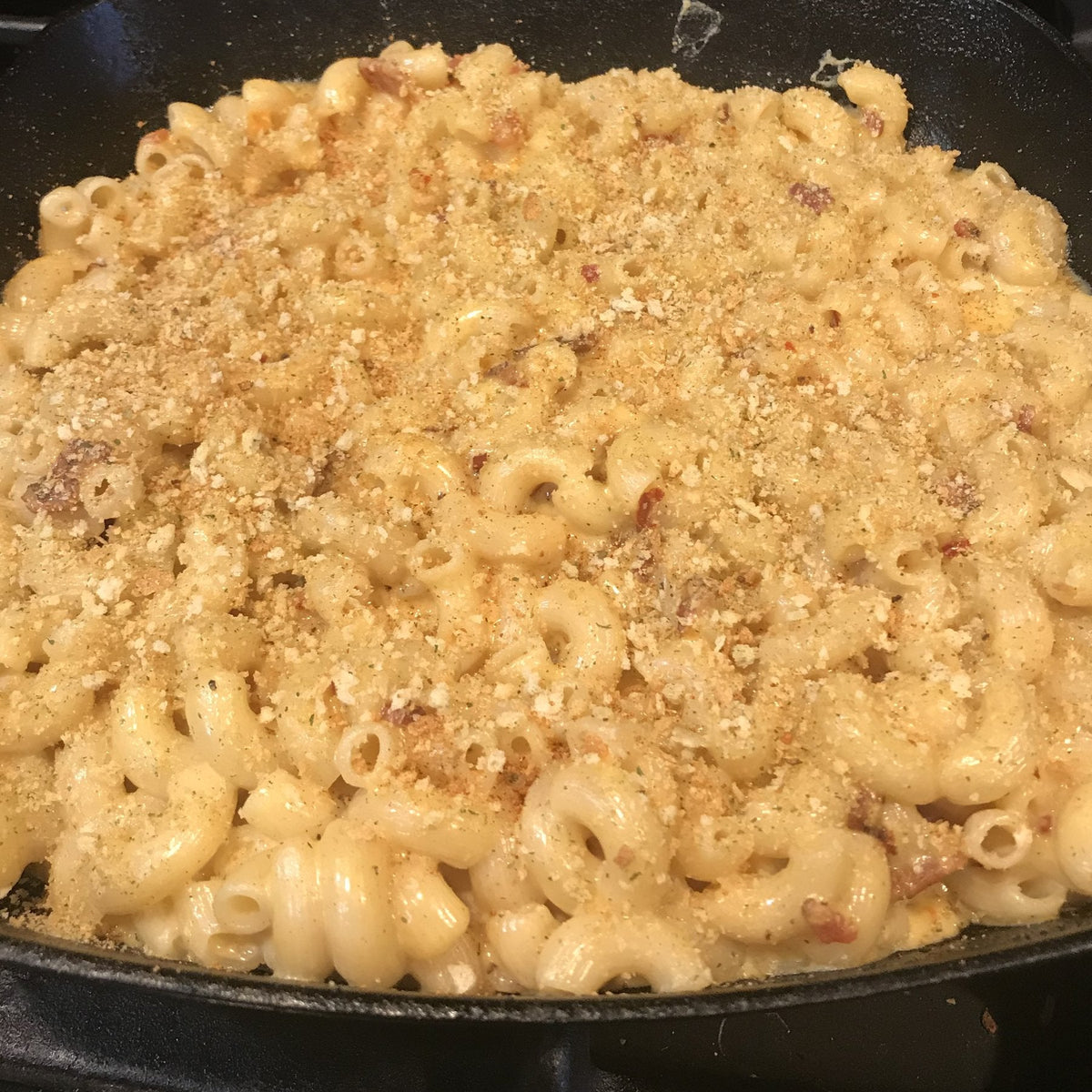 Baked mac and cheese with a golden crumb top in a cast-iron skillet