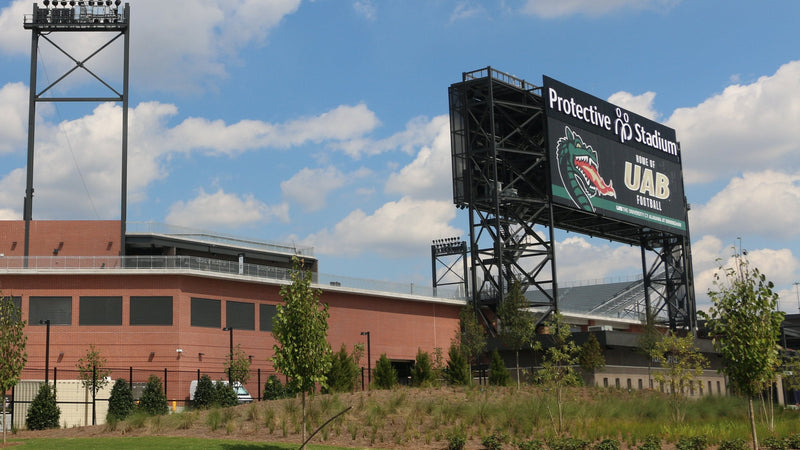 Protective Stadium in downtown Birmingham, with the stadium name on the scoreboard tower and the brick concourse building