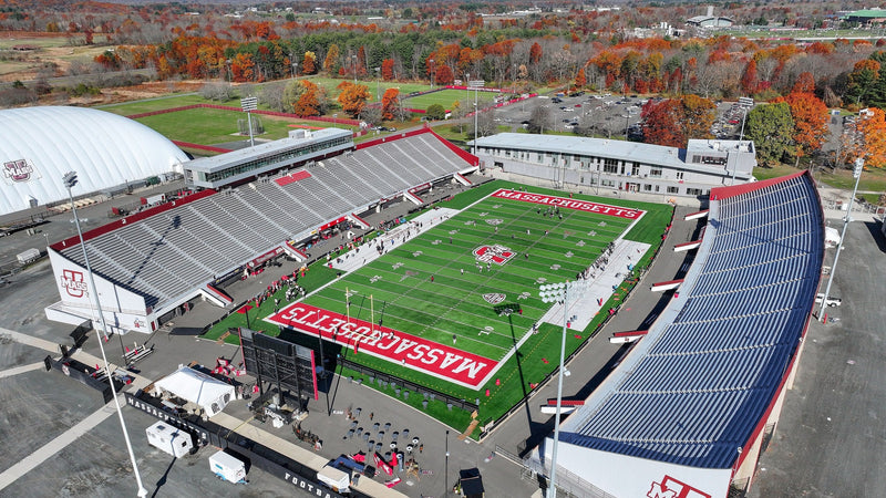 Aerial view of McGuirk Alumni Stadium in Amherst in the fall, with the lots around it and the hills behind