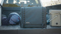 Load image into Gallery viewer, Closed dark kitchen bag in a truck bed between rolled sleeping bags and a cooler
