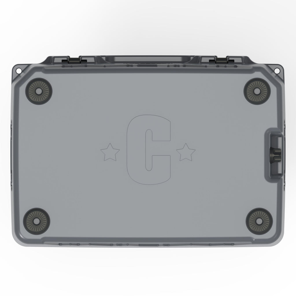 Underside of the charcoal gray hard cooler with four rubber feet and a molded C logo