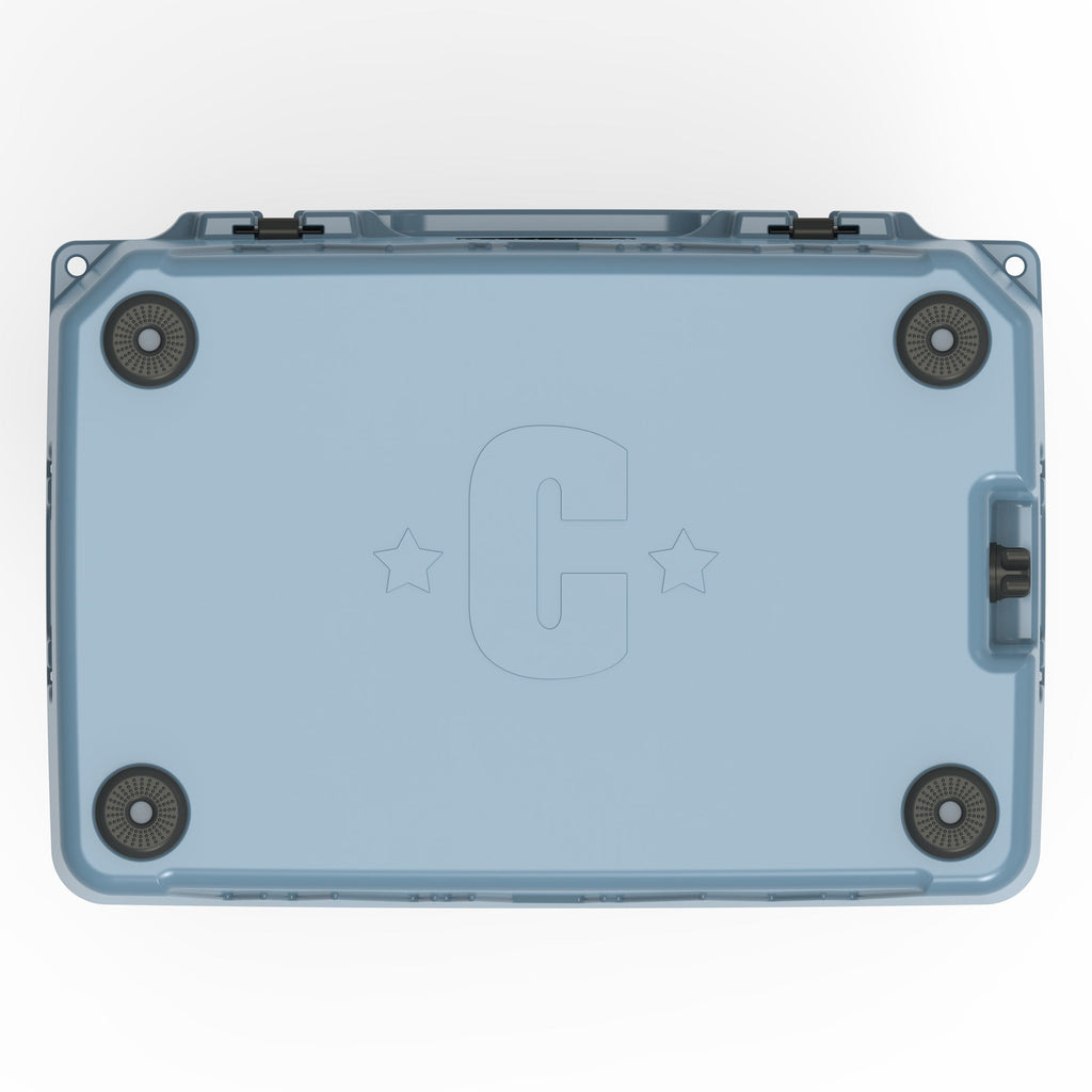 Underside of the slate-blue hard cooler with four rubber feet and a molded C logo