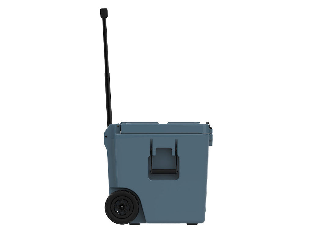 Side view of the slate-blue wheeled cooler with the handle raised, a molded grab handle and a wheel