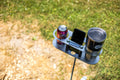 Load image into Gallery viewer, Top view of the Drinkit tray on its pole holding a soda can, a steel tumbler and a phone standing in the center slot
