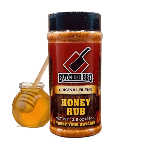 Red-labeled Butcher BBQ Honey Rub shaker, 12.5 oz, next to a jar of honey with a wooden dipper