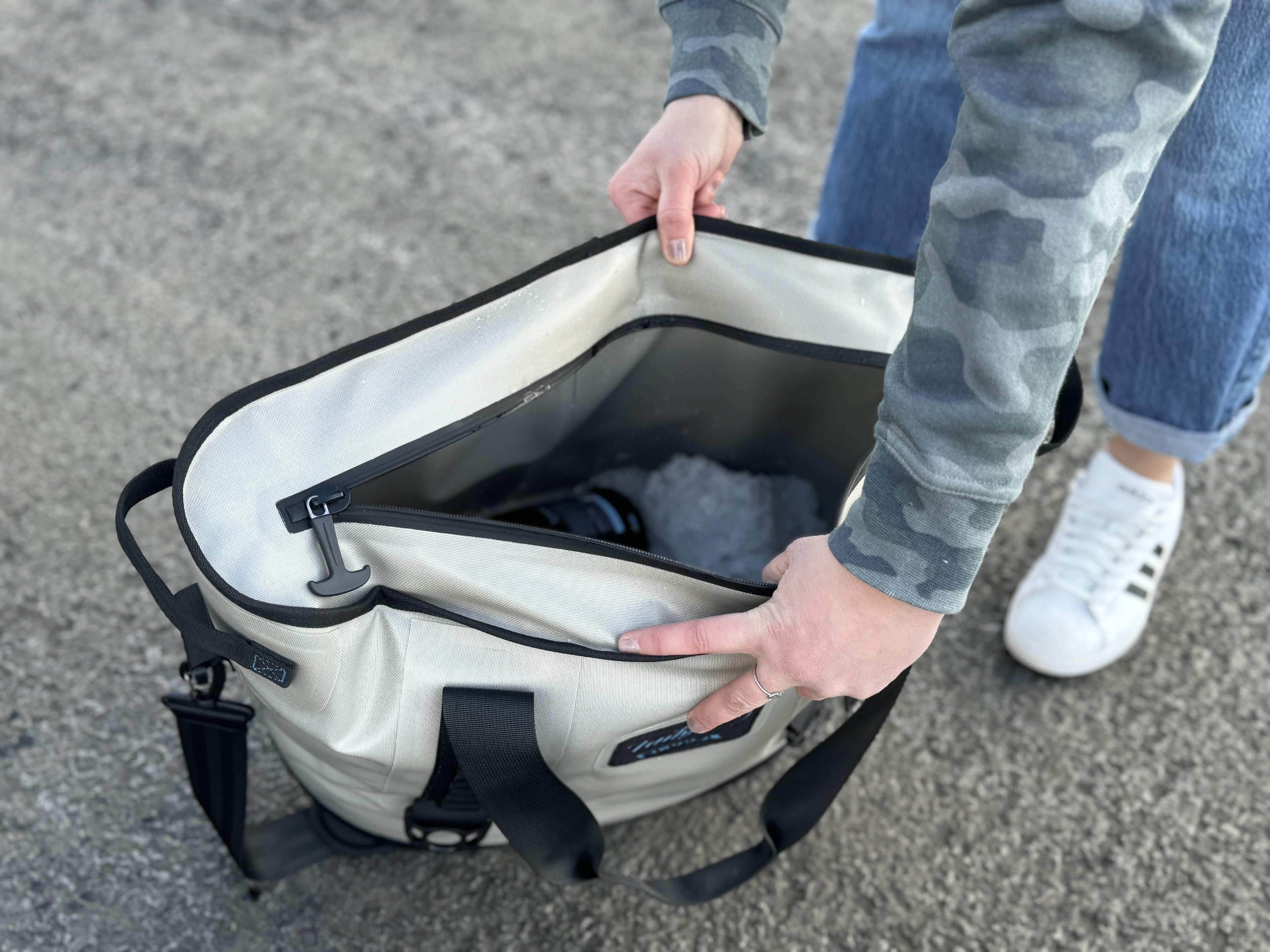 Opening the Sidekick's wide zip top on the asphalt to show the insulated inside