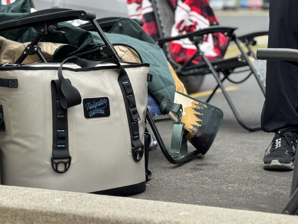 Sidekick tote cooler on the curb at a tailgate next to folding chairs and blankets