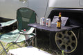 Load image into Gallery viewer, Tire Table on a truck's tire next to a camp chair, holding canned drinks and a bottle.
