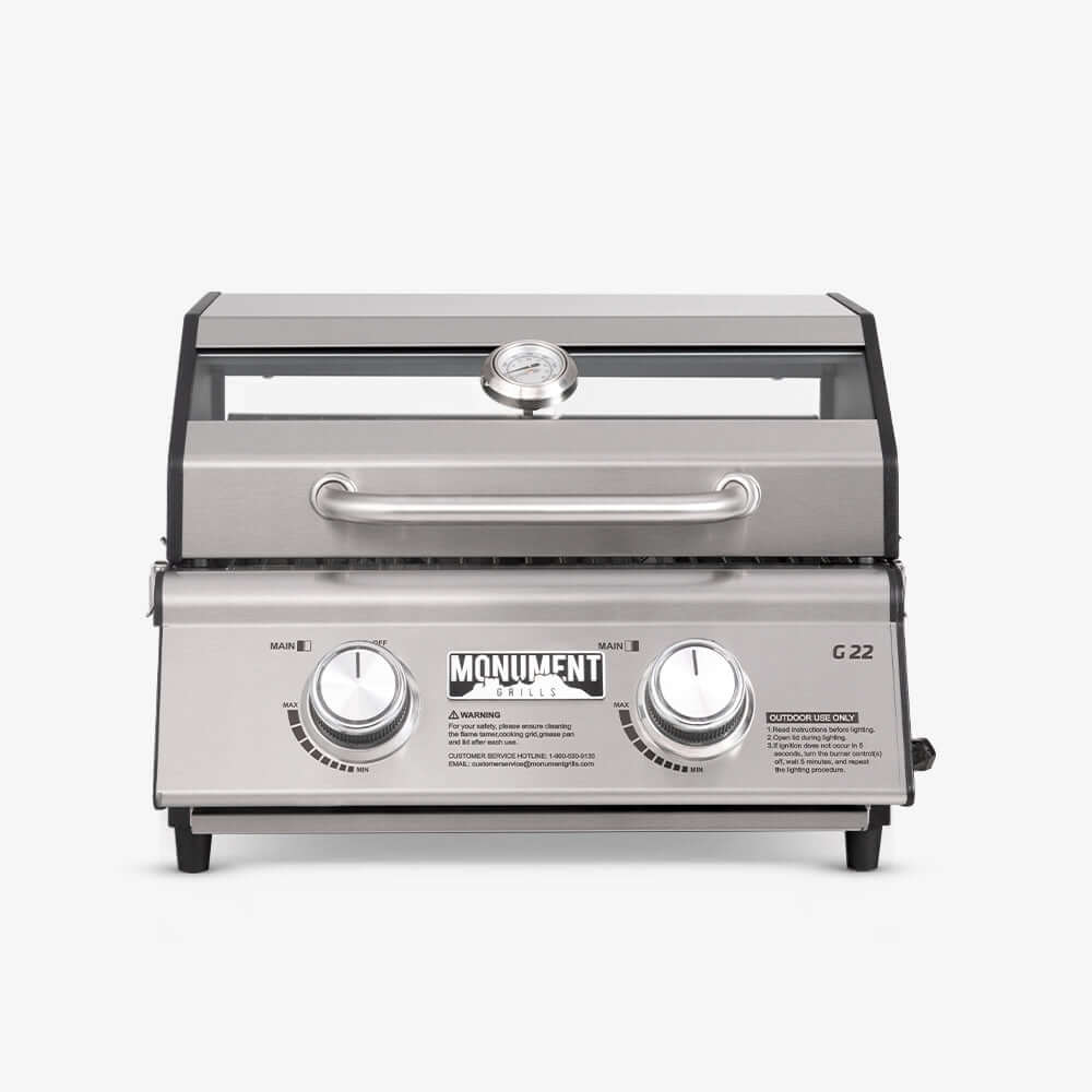 Front view of a stainless two-knob tabletop grill with a window strip in the lid and a lid thermometer