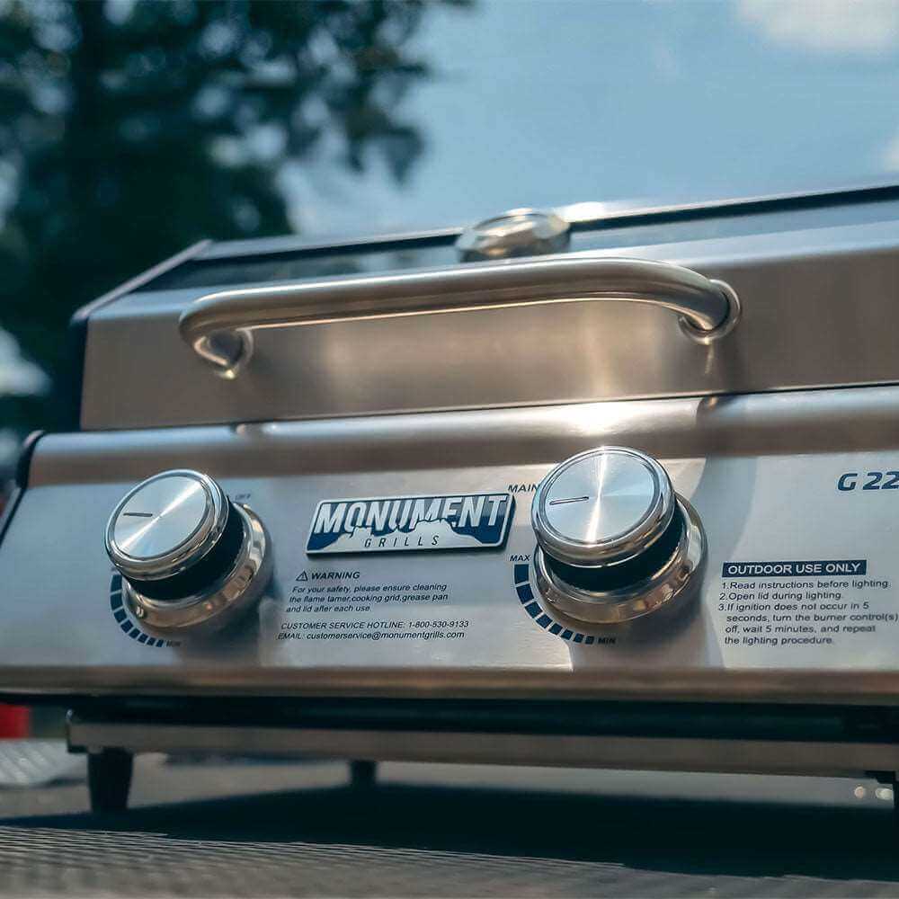 Low-angle view of the closed grill's lid handle and two control knobs outdoors