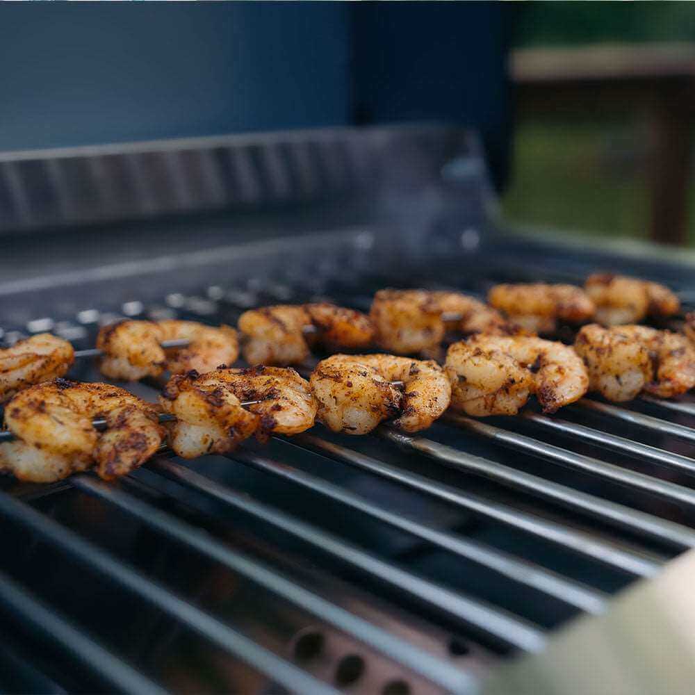 Seasoned shrimp skewers cooking on stainless grill grates