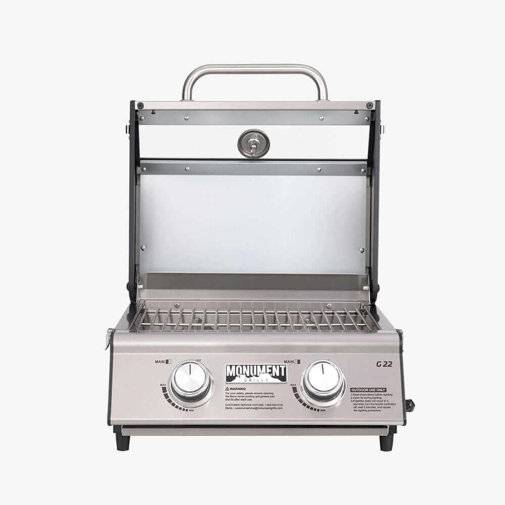 Straight-on view of the open grill showing the lid's window, thermometer and stainless grates