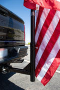 Load image into Gallery viewer, Black flagpole mounted in a pickup truck's rear hitch, flying a large American flag
