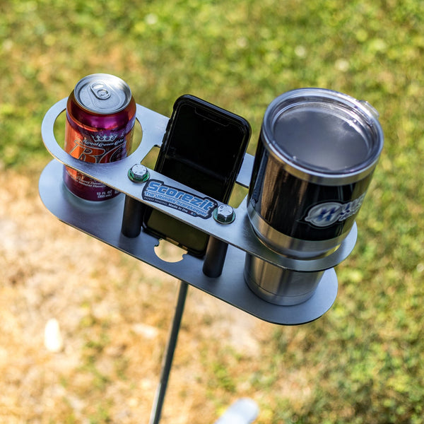 Scorezit Drinkit holder on a ground stake holding a soda can, a phone and a stainless tumbler