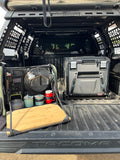 Load image into Gallery viewer, Open kitchen bag on a pickup's tailgate with its board folded out, next to a fridge in the truck bed

